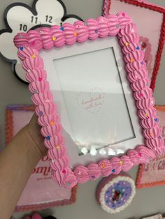 a person holding up a pink frame with hearts on it