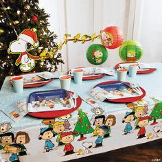 a table set up for christmas with peanuts and charlie the cat plates, cups, and napkins