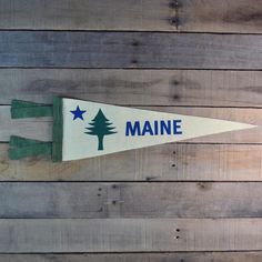 a wooden wall with a sign that says maine and a pine tree on the side