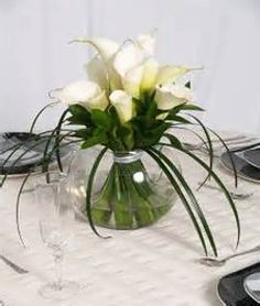 there is a vase with white flowers in it sitting on the table next to a cell phone