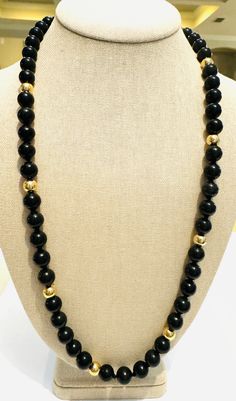 Enchanting vintage 1970s beaded necklace! This elegant necklace features 10mm, natural, hand tied, onyx beads, accented by eight 7.7mm, solid 14k yellow gold beads. The necklace is substantial, weighing 78 grams! It is 27 inches long. This gorgeous necklace is in excellent condition! Vintage Black Gemstone Beads Necklace, Vintage Black Beaded Necklace With Gemstone Beads, Classic Onyx Beaded Necklace With Black Beads, Classic Onyx Necklace With Black Beads, Formal Onyx Round Bead Jewelry, Onyx Necklace With 8mm Round Beads, Onyx Bead Necklaces With 8mm Round Beads, Onyx Bead Necklace With 8mm Round Beads, Gold Onyx Beaded Necklaces With Gemstone Beads