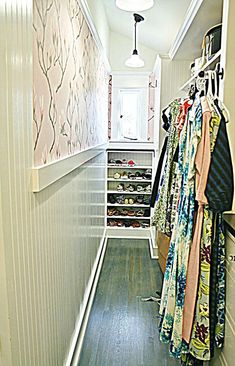 an empty hallway with clothes hanging on the wall and closet doors open to let in plenty of light