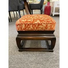 an orange and white ottoman sitting on top of a carpeted floor