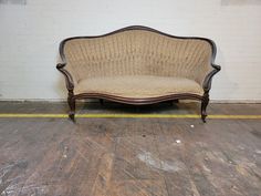 a couch sitting on top of a hard wood floor next to a white brick wall