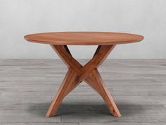 a round wooden table sitting on top of a hard wood floor covered in white walls