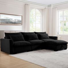 a living room with a large black couch and white rugs on the hardwood floor