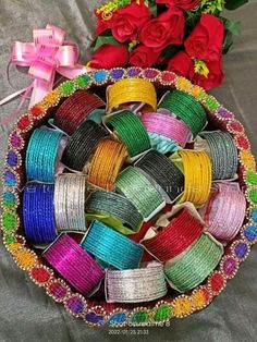 there are many different types of ribbons in the bowl on the table next to roses