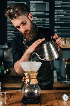 a man pours coffee into a glass pitcher