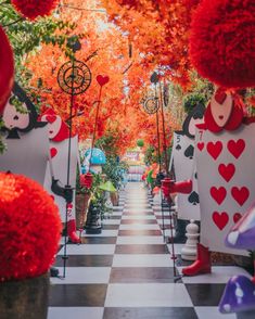 an outdoor garden with lots of red and white decorations on the trees, plants and flowers in pots