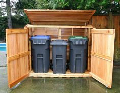 an outdoor storage shed with three trash cans in it