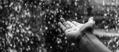 someone is holding their hand out in front of a window with rain drops on it