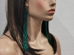 a mannequin head with green earrings on it's face and long hair