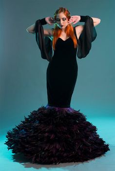 a woman with long red hair wearing a black dress and holding her hands behind her head