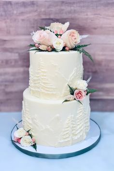 a wedding cake with white frosting and pink flowers on the top is sitting on a plate