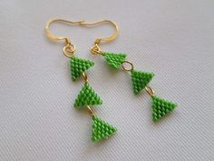 These elegant geometric earrings are made with three small woven triangles stitched together using color lined green lime Delicas. The triangles are linked together with gold plated jump rings, which then hang from gold plated ear wires. The earrings measure 1.5 inches long. Handmade Green Geometric Earrings, Handmade Green Triangle Earrings, Handmade Green Triangle Jewelry, Triangle Earrings, Rochester Ny, Dec 1, Color Lines, Geometric Earrings, Glass Earrings