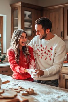 a man and woman standing in front of a kitchen counter with cookies on the counter