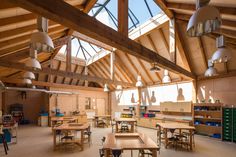 an empty classroom with wooden desks and hanging light fixtures on the ceiling, is shown in this image