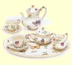 a tea set with butterflies and flowers on it