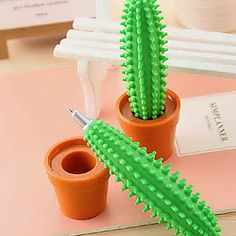 two cactus plants in small pots with toothbrushes on the top and another plant next to them