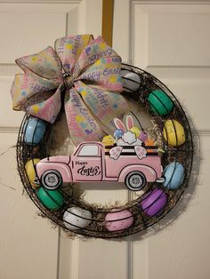 a pink truck decorated with easter eggs is hanging on the front door wreath that says happy easter