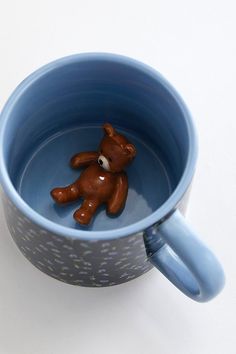 a brown teddy bear sitting in a blue cup