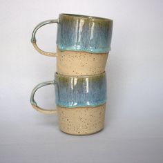 two coffee mugs stacked on top of each other