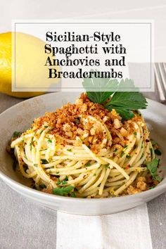 a white bowl filled with spaghetti and topped with parsley next to a lemon wedge