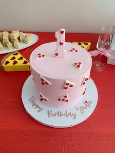 a pink birthday cake sitting on top of a table