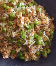 rice and peas are mixed together in a black bowl on top of a blue table cloth