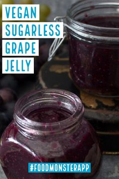 a jar filled with blueberry jam next to grapes