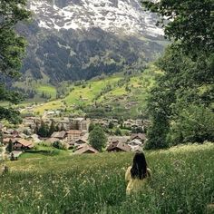 a woman sitting on top of a lush green hillside