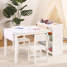 a child's desk and chair set up in front of a potted plant