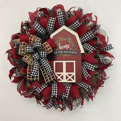 a red and black wreath with a house on the top that says, home on the holidays