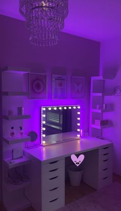 a white desk topped with a computer monitor under a purple lit up mirror and lights