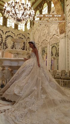 a woman in a wedding dress standing next to a fountain with chandelier hanging from the ceiling