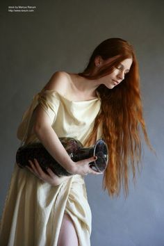 a woman with long red hair holding a purse