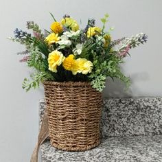 a basket filled with yellow and white flowers on top of a counter next to a wall