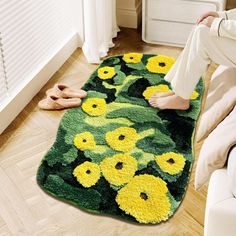 a woman is sitting on the floor in front of a rug with yellow and green flowers