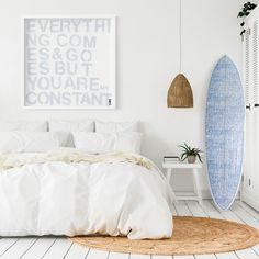 a white bedroom with a surfboard on the wall