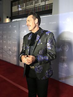 a man in a suit standing on a red carpet