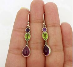 A majestic Amethyst earring with glittering Peridot gemstone set beautifully in simple sterling silver earring will make these an instant favourite. Jewelry that can add glamour to your outfits. Precious gems for your precious one. Gemstone:- Amethyst, Peridot Gemstone Shape:- Pear,Round Gemstone Size:- 7 mm x 10 mm Pear(Amethyst), 6 mm x 8 mm Pear(Peridot), 4 mm x 4 mm Round(Amethyst) Material:- Solid 925 Sterling Silver Main Stone Creation:- Natural Dimension:- 8 mm Wide x 42 mm Long with hook                                                      ❏ BENIFITS OF SILVER > Healing Properties > Protects From Bacteria > Hypoallergenic > Pain Relief ❏ BENIFITS OF AMETHYST > Natural Tranquilizer > Fights Addictions > Dissolves Negative Energy > Physical Healing > Psychic Abilities ❏ BENIFITS OF P Purple Sterling Silver Teardrop Dangle Earrings, Purple Multi-stone Teardrop Earrings, Teardrop Multi-stone Amethyst Earrings, Sterling Silver Multi-stone Teardrop Earrings, Purple Multi-stone Sterling Silver Earrings, Purple Teardrop Multi-stone Jewelry, Sterling Silver Multi-stone Drop Earrings, Amethyst And Peridot, Glamorous Jewelry