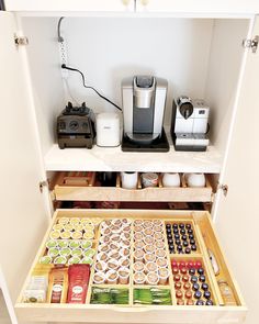 an open drawer with coffee and tea in it next to a toaster, espresso machine and other items