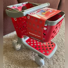 a red shopping cart sitting on top of a carpeted floor