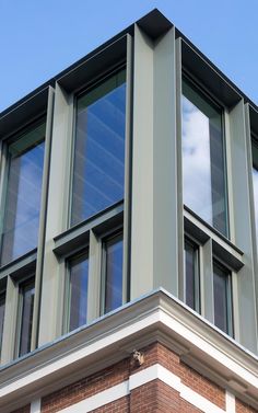 the corner of a building with several windows on it's side and a sky background