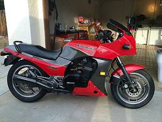 a red motorcycle parked in front of a garage