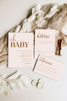 the wedding stationery is laid out on top of feathers and paper with gold foil lettering