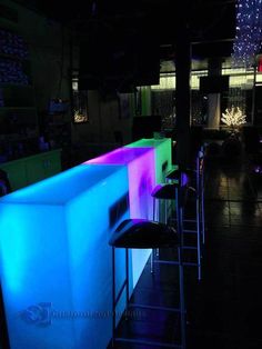 an illuminated bar in a dark room with stools