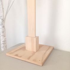 a tall wooden sculpture sitting on top of a table next to a white tree in the background