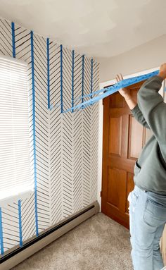 a woman is measuring the length of a room with tape on it's wall