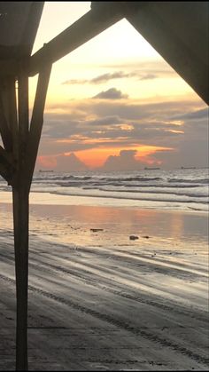 the sun is setting at the beach with waves coming in